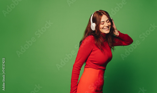 Cheerful young woman enjoying music on headphones in modern studio