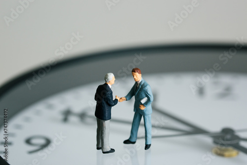 時計の上で交渉するビジネスマンの人形 © taa22