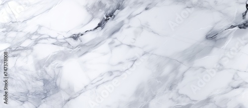 Detailed view of a white marble texture background, showcasing the intricate patterns and veins characteristic of marble. The smooth surface and unique markings create a visually interesting backdrop.