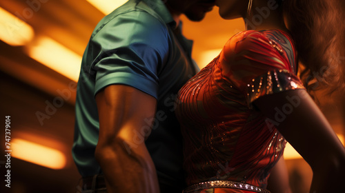 Sensual Latin American couple in vibrant silky clothes dancing seductive salsa in a club. Beautiful young people feeling attracted to each other, having fun at a social dance party. Romance, passion. photo