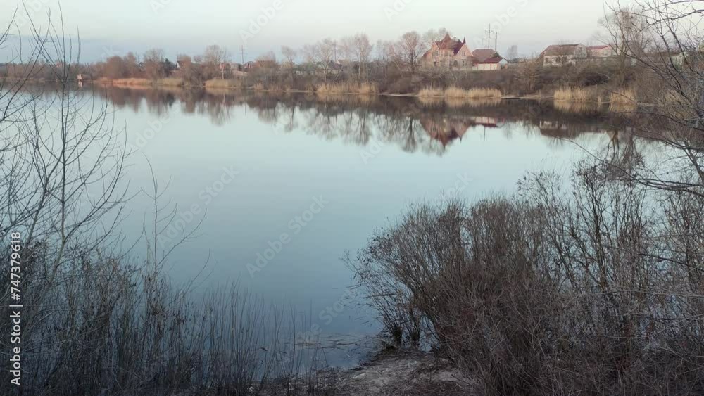 evening landscape on the river with reflection in the water. The colorful cloudy sky and trees are reflected in the calm river water. Grass and trees grow on the banks of the river. Houses are reflect evening landscape on the river with reflection in the water. The colorful cloudy sky and trees are reflected in the calm river water. Grass and trees grow on the banks of the river. Houses are reflect