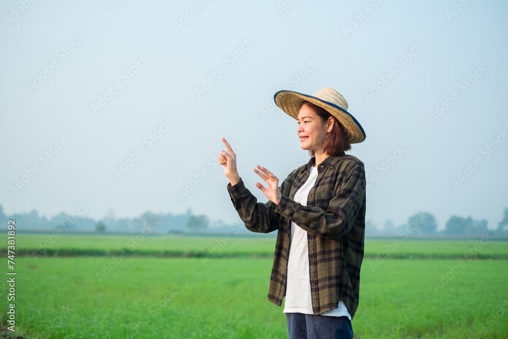 Asian female farmer dressed in brown blouses, jeans Stand and touch the screen in the air.