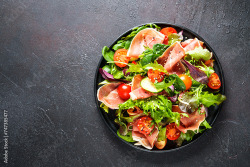 Healthy food. Fresh salad with jamon, green salad leaves and tomatoes. Top view with space for text.