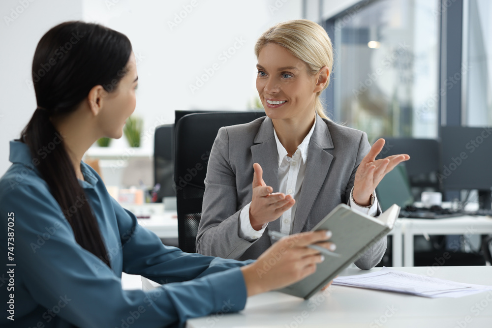 Lawyers with notebook working together at table in office Lawyers with notebook working together at table in office