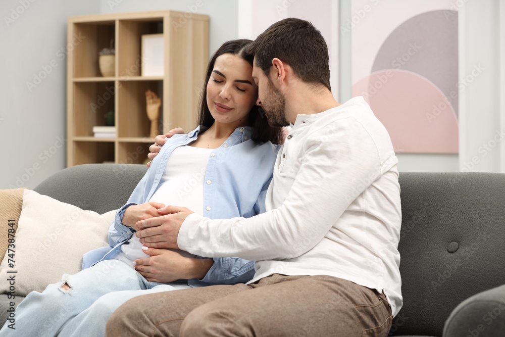 Pregnant woman with her husband on sofa at home Pregnant woman with her husband on sofa at home