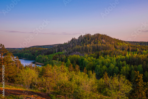 Small mountain in Sweden during a nice sunset with some forests and a lake in the forground photo