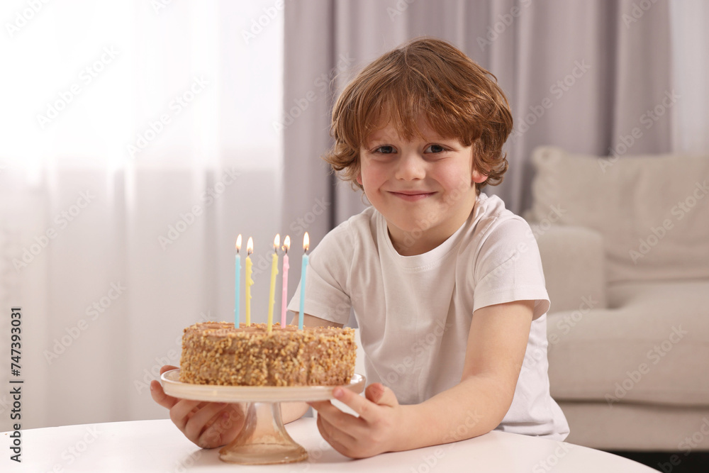 Cute boy with birthday cake at table indoors Cute boy with birthday cake at table indoors