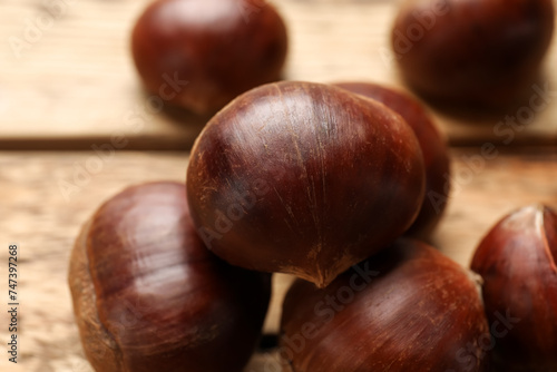 Sweet fresh edible chestnuts on wooden table  closeup