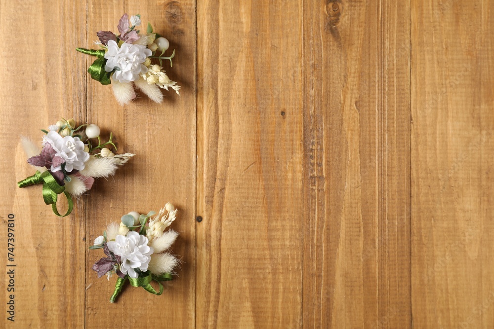 Stylish boutonnieres on wooden table, flat lay. Space for text Stylish boutonnieres on wooden table, flat lay. Space for text