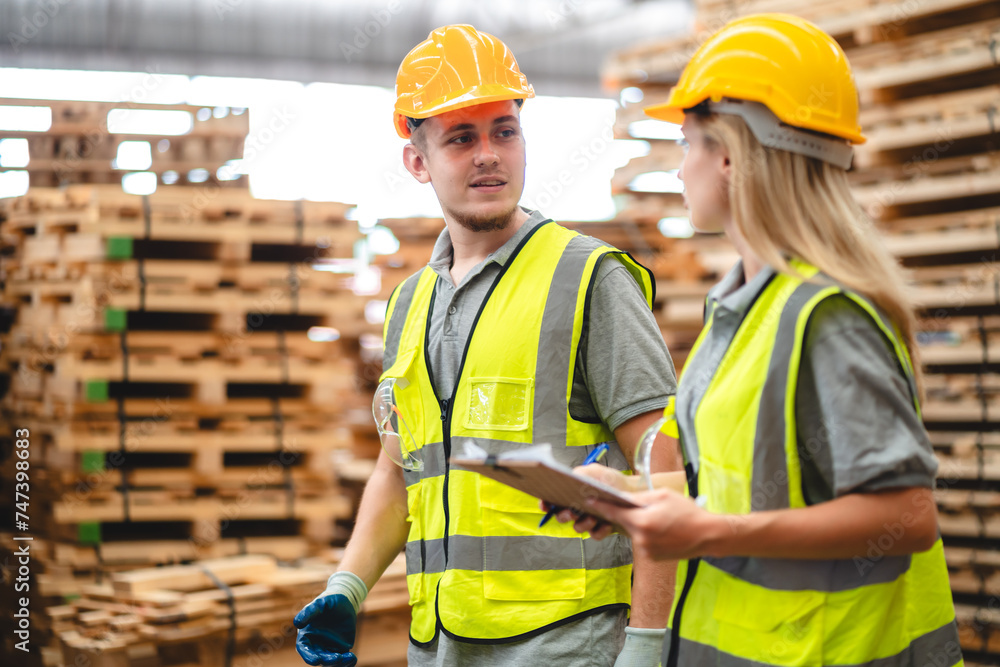 Man and woman workers with clipboard discussing working and checking stock inventory wood plank material for making wooden pallet products at warehouse industrial factory, woodwork production Man and woman workers with clipboard discussing working and checking stock inventory wood plank material for making wooden pallet products at warehouse industrial factory, woodwork production