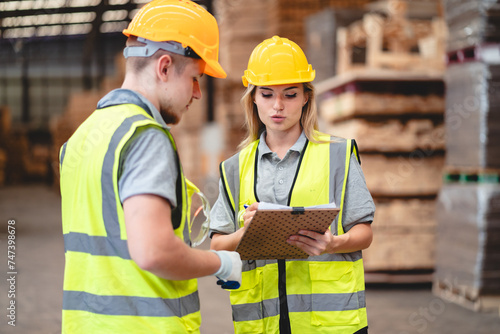 Man and woman workers with clipboard discussing working and checking stock inventory wood plank material for making wooden pallet products at warehouse industrial factory, woodwork production