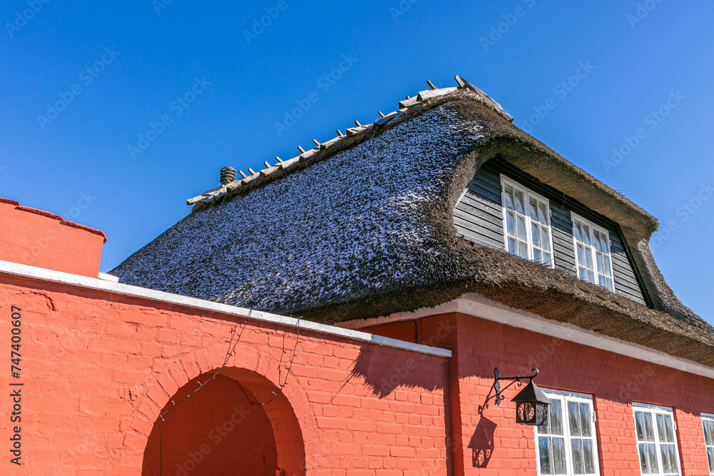 Fototapeta premium 23-03-2023 Svogerlev, Denmark: Red restaurant with thatched roof blue sky