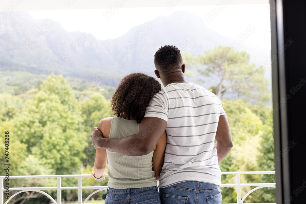 Biracial African American couple embrace, overlooking a mountainous landscape at home Biracial African American couple embrace, overlooking a mountainous landscape at home
