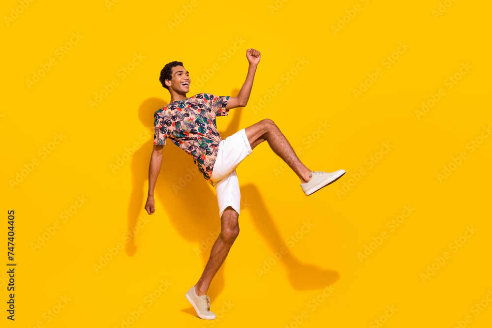 Full body length photo of funky young guy big steps motion looking empty space brand summertime clothes isolated on yellow color background