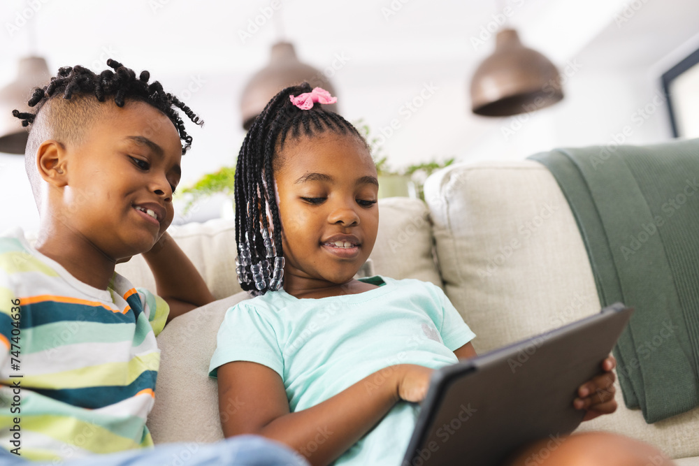 African American brother and sister are focused on a tablet indoors African American brother and sister are focused on a tablet indoors