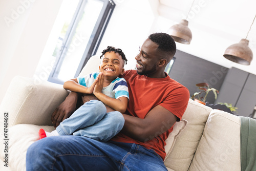 African American father and son share a joyful moment on a sofa