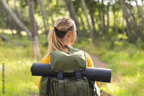 Young woman with a backpack stands amidst greenery on a hike