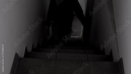 A scary amateur video of a man or a maniac with a knife, or an ax man climbing the steps in the dark. Horror, mysticism, crime, murderer.