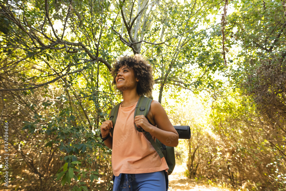 Young biracial woman with curly hair enjoys a hike in a lush forest Young biracial woman with curly hair enjoys a hike in a lush forest