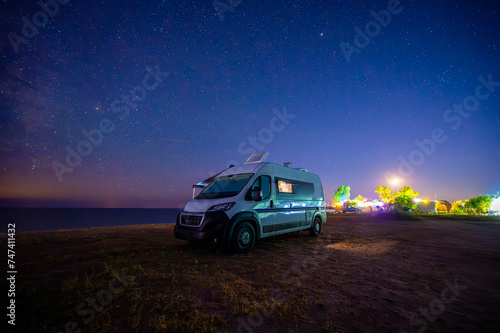 Campervan or motorhome parked on the beach in Greece under the stars and milky way. Tourists enjoying and relaxing on the beach with RV campervan on family vacation. photo