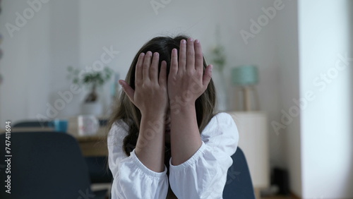 Schilderij op canvas Child regretting past mistakes by covering face in shame and hitting her own head and forehead with hand