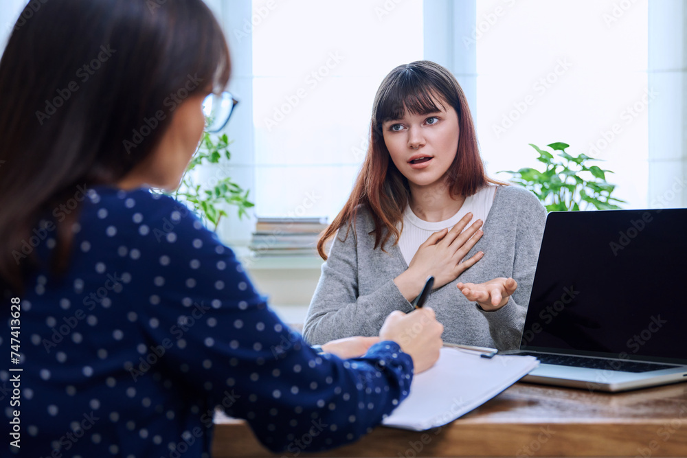 Sad, serious teenage girl at session in office of mental professional