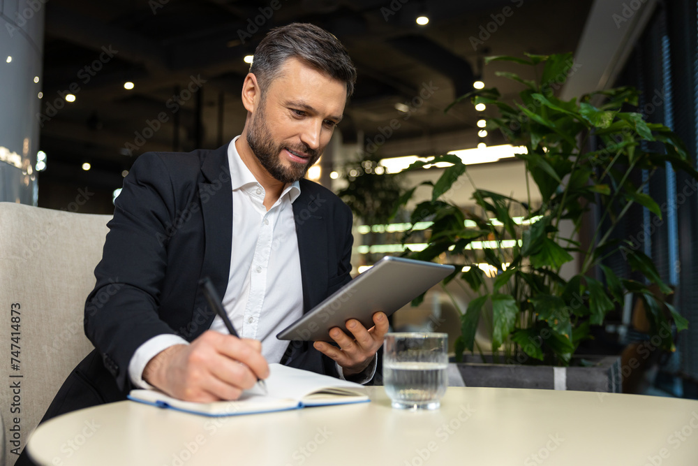 Positive young manager with tablet in hands working in the office Positive young manager with tablet in hands working in the office
