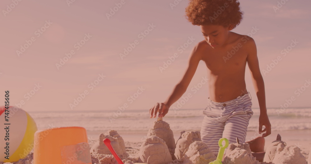 Fototapeta premium African american young boy building sand castles at the beach