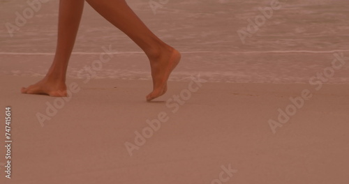Low section of a woman walking at the beach