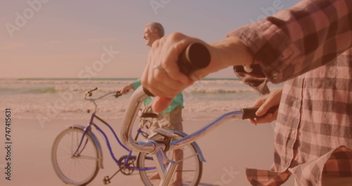 Happy caucasian senior couple riding bicycles together at the beach