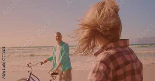 Happy caucasian senior couple riding bicycles together at the beach