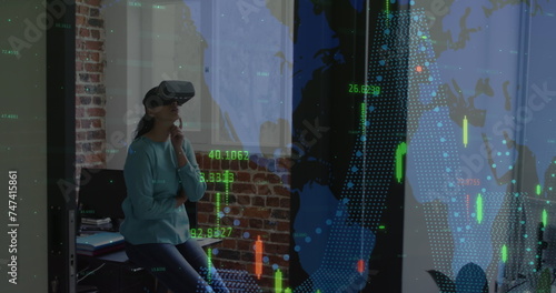 Image of financial data processing over businesswoman wearing vr headset in office