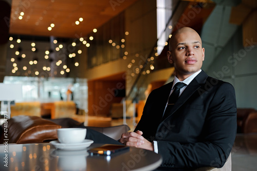 African american businessman sitting near smartphone and coffee in restaurant of business center