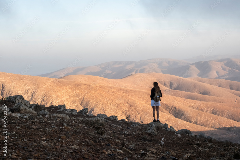 Una mujer visitando el mirador en Fuerteventura y disfrutando de la grandeza de las montañas áridas y bonitas