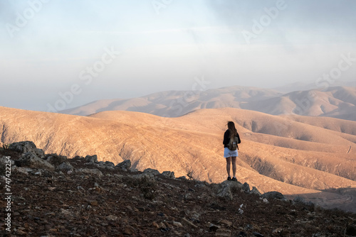 Una mujer visitando el mirador en Fuerteventura y disfrutando de la grandeza de las montañas áridas y bonitas photo