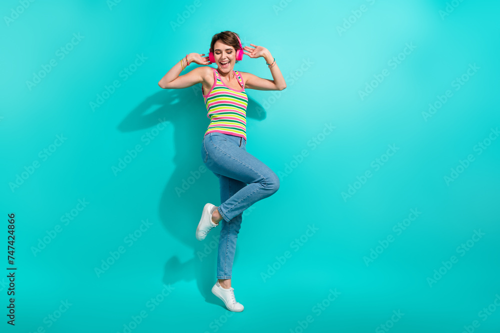 Full length portrait of positive overjoyed person enjoy music headphones dance empty space isolated on turquoise color background