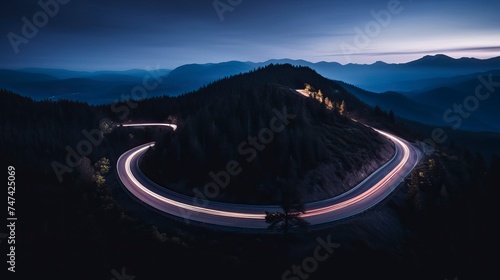Aerial panoramic view of curvy mountain road with trailing lights at night photo