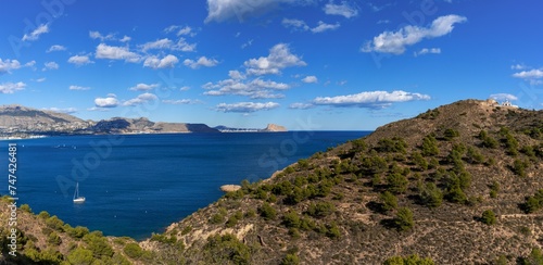 sailboat moored in a bay of the Serra Gelada Natural Park with the Albir Lighthouse in the background