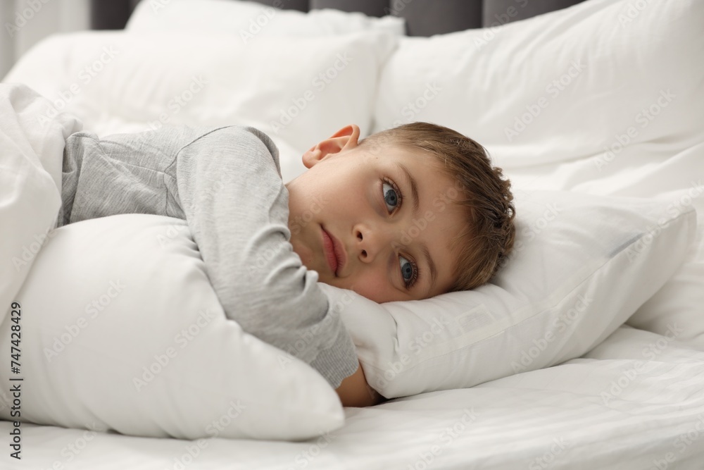Sad little boy in bed at home Sad little boy in bed at home