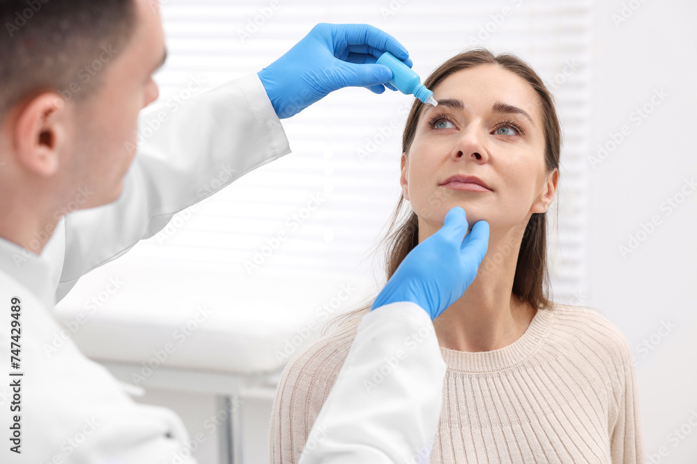 Doctor applying medical drops into woman's eye indoors Doctor applying medical drops into woman's eye indoors