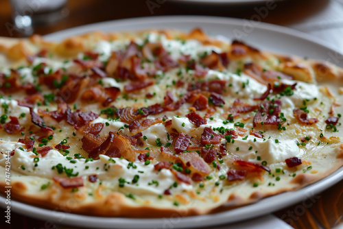 A plate of Flammkuchen, a traditional dish from the region of Alsace, which is a thin crust pizza-like dough topped with , onions, and bacon.