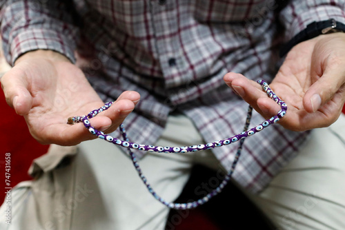 Muslim man praying with prayer beads (Masbahah ). Close-up.