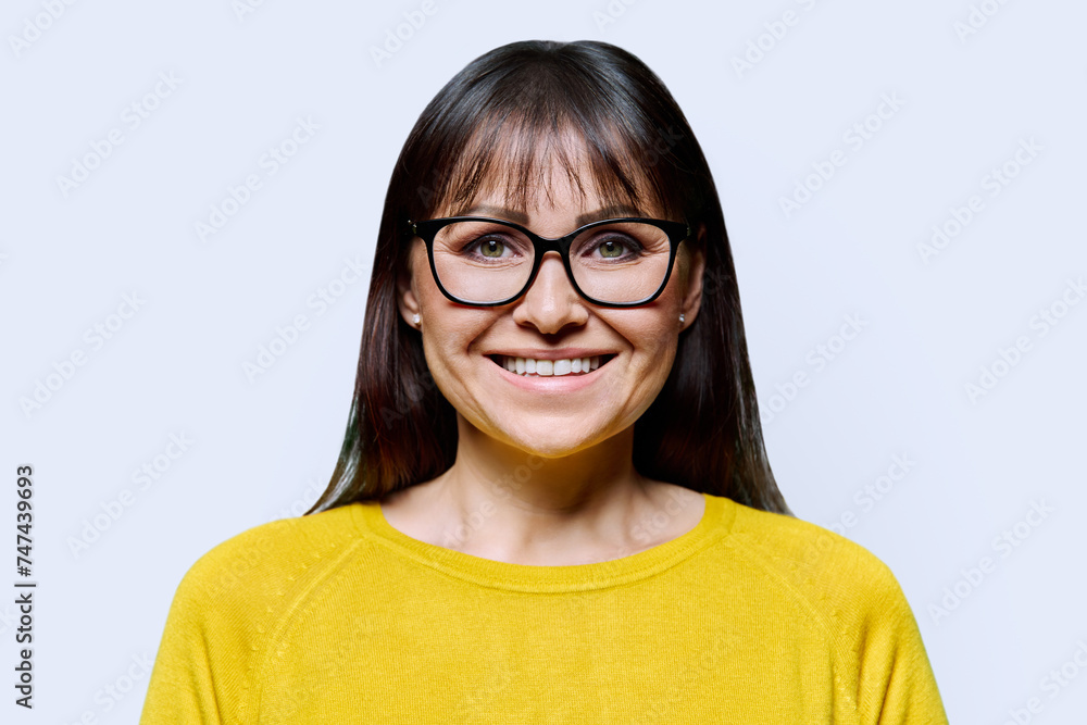 Headshot portrait of smiling mature woman on white studio background