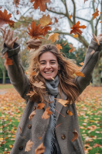 Woman joyfully throwing autumn leaves in the air. Perfect for seasonal promotions