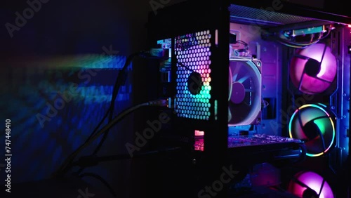 Desktop gaming PC case with rainbow lighting. RGB light is projected onto the wall in the dark. photo