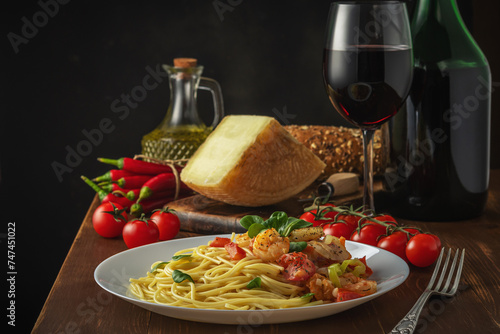 Spaghetti with shrimps, cherry tomatoes and spices on wooden background. Food background.
