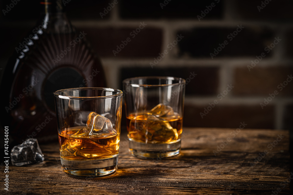Whiskey with ice in glasses and bottle, dark background, copy space Whiskey with ice in glasses and bottle, dark background, copy space