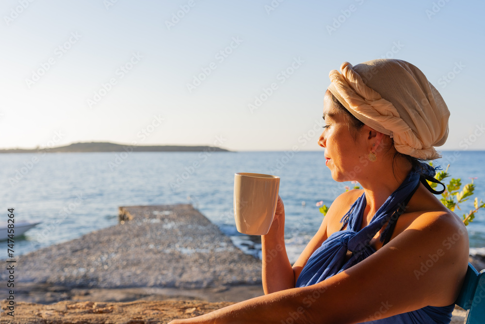 Beautiful woman relaxing with her eyes closed while enjoying her coffee in a typical Greek tavern in southern Greece
