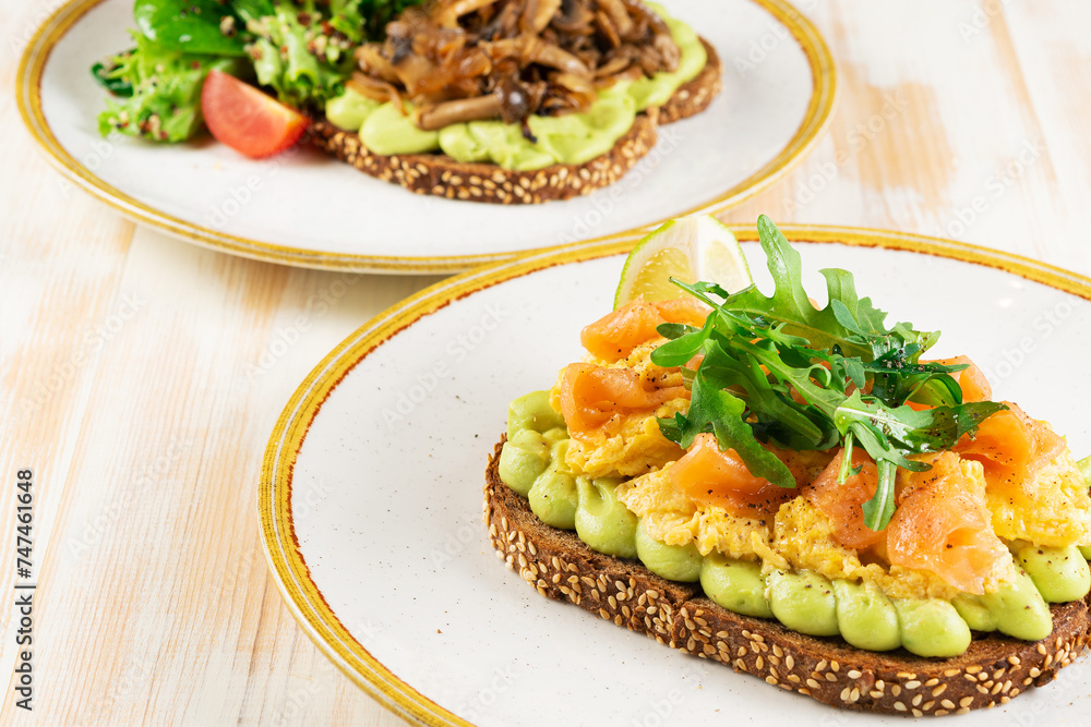 Two sandwiches with salted salmon and mushrooms on wooden backround. Healthy breakfast.