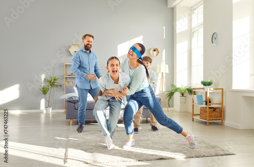 Happy family with children is playing hide and seek at home in the living room. They are enjoying leisure time together, engaging in a fun and interactive game that brings joy to the whole family.